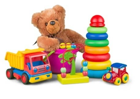 A collection of colorful children's toys including a teddy bear, stacking rings, a dump truck, and a train.